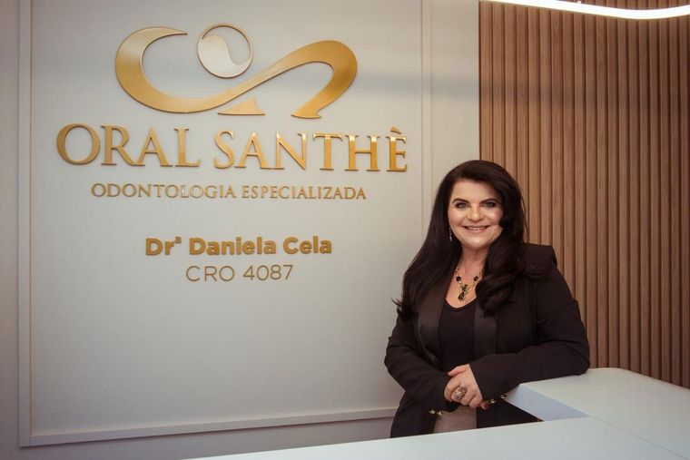 Dra. Daniela Cela diante da parede com a marca Oral Santhè