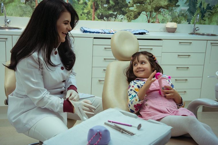 Dra. Daniela Cela atendendo uma menina na cadeira, na sala infantil