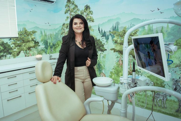 Dra. Daniela Cela na sala infantil, com o mural de floresta ao fundo