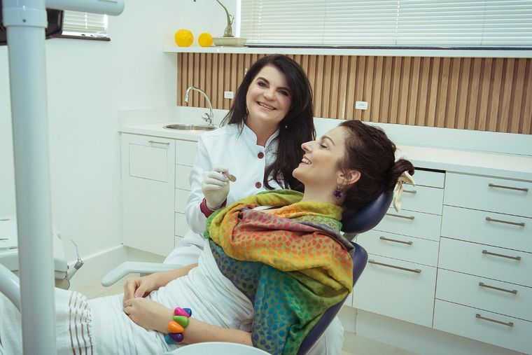Dra. Daniela Cela conversando com uma paciente adulta na cadeira
